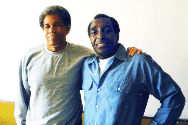 Photo of Albert Woodfox on the left, arm in arm with Kenny Zulu Whitmore on the right